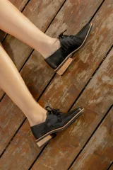 Zapato acordonado de cuero vacuno color marrón oscuro, con suela de goma, horma cuadrada y tacón bajo.