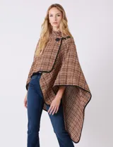 Ruana tejida de la marca Jones New York, con estampado a cuadros en tonos marrón, beige y blanco. Presenta cuello alto y cierre frontal con botón trenca y botón a presión interno. Los bordes están ribeteados en negro.
