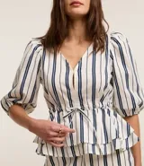 Blusa de sarga a rayas verticales blancas y azules, con cuello en V, mangas cortas abullonadas, lazo en la cintura y volado en el bajo.