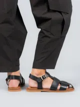 Sandalias bajas doradas con diseño de tiras entrecruzadas y hebilla lateral.