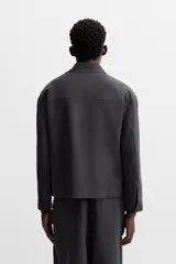 Sobrecamisa verde oscuro de corte cuadrado, con cuello solapa, manga larga con puños abotonados, bolsillos de parche en el pecho y bolsillos laterales en la cadera. Cierre frontal con botones.