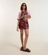 Short pollera de cuero sintético color bordó, con bolsillos delanteros con solapa y cierre frontal con cremallera.