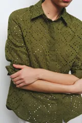Camisa amarilla de cuello solapa y manga larga acabada en puño. Detalle de bordados perforados a tono. Cierre frontal con botones ocultos por solapa.