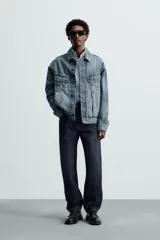 Cazadora de denim de algodón de corte regular, color azul medio lavado. Presenta cuello solapa, manga larga con puños abotonados, dos bolsillos de solapa en el pecho y bolsillos laterales en la costura de la cadera. Cierre frontal con botonadura.