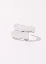 Set de dos anillos plateados ajustables de acero quirúrgico hipoalergénico. Uno es un anillo abierto con forma entrelazada y el otro es un anillo con diseño calado oval.