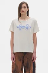 Remera color crudo de algodón lavado con cuello redondo, manga corta y calce oversized. Estampado frontal con dos flores abstractas en color celeste.