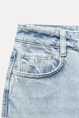 Pantalón de jean color crudo, de tiro alto, corte recto y largo tobillero. Tiene cinco bolsillos, cierre frontal con cremallera y botón metálico.