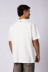 Remera de hombre color crudo, corte oversize, confeccionada en algodón grueso con textura micropanal. Diseño liso sin logos, con costura en forma de 'X' en la espalda. Ideal para un look casual y relajado.