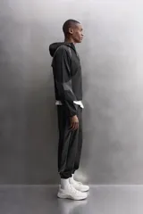 Chaqueta deportiva negra con paneles grises en hombros y laterales, capucha ajustable, cierre frontal con cremallera, bolsillos laterales con cremallera y puños elásticos. Zara Athleticz.