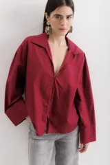 Camisa manga larga color borgoña, con cuello camisero y cierre frontal con botones.