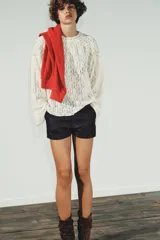 Top de encaje color blanco, con cuello redondo, mangas largas acampanadas y detalle de tachas metálicas en cuello y hombros. Cierre en la espalda con abertura y botón.