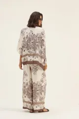 Pantalón palazzo de seda color crema con estampado floral en tonos marrones y cintura elastizada con cordón ajustable.