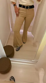 Pantalón de vestir color beige, de tiro alto, corte recto y terminación acampanada.