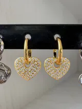 Par de aros dorados con forma de argolla y dije de corazón cubierto de circonitas blancas.
