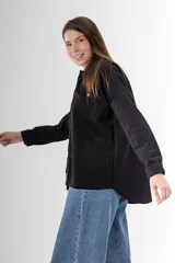 Camisa negra de gamuza sintética, corte amplio y largo asimétrico.