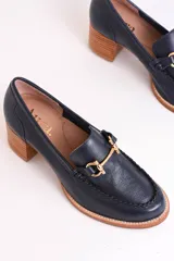 Mocasín de cuero color azul marino con aplique metálico dorado y taco de madera.