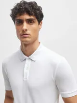 Chomba blanca de piqué de algodón con cuello clásico, tapeta de dos botones y logo bordado en el pecho.
