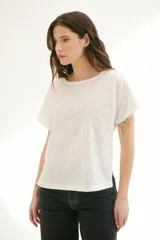 Blusa blanca con estampado de hojas en relieve, cuello redondo y mangas cortas.