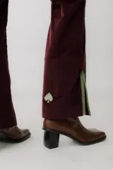 Pantalón de pana marrón con corte acampanado y abertura en el ruedo.