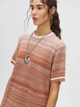 Vestido corto tejido a rayas horizontales en tonos marrones y beige, con cuello redondo y mangas cortas con ribete blanco. Corte recto y holgado.