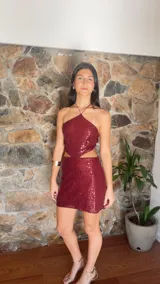 Minivestido borgoña de lentejuelas con escote halter, espalda descubierta y aberturas laterales en la cintura.