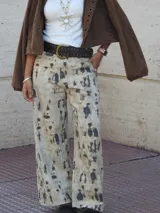 Pantalón de jean recto y ancho, de tiro medio, con estampado de manchas irregulares en tonos beige y gris oscuro.