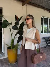 Chaleco sin mangas color beige claro, con bordados florales en relieve y abertura frontal.