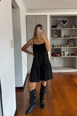 Vestido corto negro con breteles finos y falda con volados.