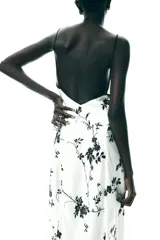 Vestido largo blanco con estampado de flores negras, escote pico y tirantes finos con ribete negro.