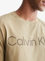 Remera de algodón color beige con diseño holgado, cuello redondo y logo de Calvin Klein estampado en la parte delantera.