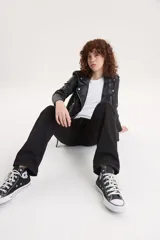 Campera biker negra de cuero sintético con cuello solapa, cierre cruzado con cremallera, bolsillos con cremallera y cinturón ajustable.