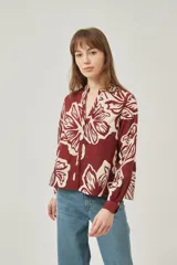 Camisa de poliéster con estampado floral en tonos borgoña y crema, corte holgado, cuello mao y cierre frontal con botones.