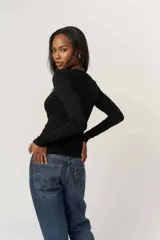 Remera de manga larga color negro, confeccionada en jersey liviano con escote en V y calce ajustado al cuerpo.