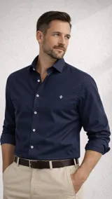 Camisa de manga larga color azul marino, con cuello clásico y botones blancos. Presenta un pequeño logo bordado en blanco en el pecho.