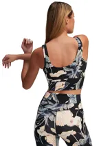 Musculosa deportiva corta con estampado floral en tonos pastel sobre fondo negro.