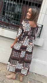 Vestido largo con estampado floral en tonos marrones, blancos y negros. Tiene escote en V, mangas cortas y corte holgado.
