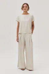 Blusa color crema de lino metalizado, de calce recto, con cuello bote y mangas cortas.