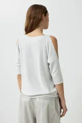 Sweater de tejido de punto fino con efecto lurex brillante, color plateado claro. Presenta un escote bote y aberturas en los hombros (cold shoulder) con mangas tres cuartos.