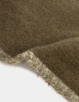 Bufanda tejida color crema con flecos en los extremos y etiqueta de cuero sintético negra.