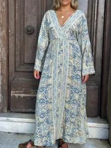 Vestido largo fluido con escote en V y mangas abullonadas 3/4. Presenta un estampado tipo paisley en tonos celeste, beige y gris.