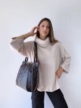 Bolso tipo tote de cuero negro con costuras a la vista en color camel. Tiene doble asa de hombro y está forrada en tela.