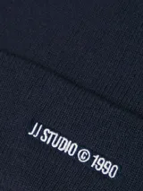 Gorro de lana azul marino con dobladillo y bordado frontal con la inscripción "JJ STUDIO © 1990".