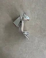 Sandalia de fiesta dorada con tiras finas cruzadas en el empeine, pulsera con hebilla al tobillo y taco geométrico.