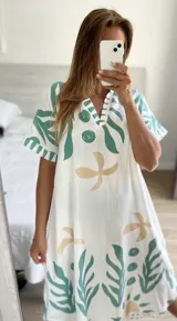 Túnica blanca con estampado de hojas y flores en verde agua y beige, con escote en V y mangas cortas.