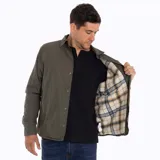 Sobrecamisa Merrell color verde oliva, confeccionada en algodón suave y resistente. Cuenta con cuello clásico, cierre frontal con botones a presión, bolsillo de parche en el pecho izquierdo con etiqueta de la marca y puños con botón.