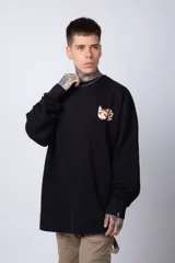 Buzo color crema de corte oversize confeccionado en tela friza con cuello redondo y puños y cintura acanalados. Presenta un pequeño bordado en el frente y un estampado grande en la espalda.