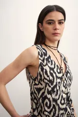 Chaleco sin mangas con escote en V y cierre frontal de botones dorados. Presenta un estampado tipo ikat o batik en blanco y negro.