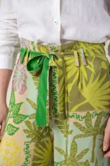 Pantalón ancho de tela blanca con estampado de flores azules, cintura alta con cordón ajustable y bolsillos laterales.