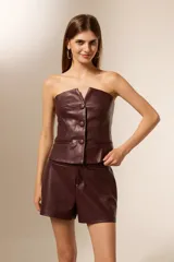 Top sin mangas de cuero sintético color borgoña, con cuello strapless, pinzas en el busto y cierre frontal con tres botones grandes.