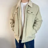 Chaqueta de pana color beige con forro de corderito en el cuello y el interior. Tiene cierre con botones, bolsillos en el pecho y bolsillos laterales.